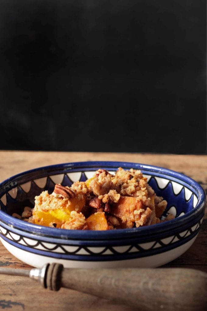 Pumpkin Spice Crisp (Crumble) with Gingerbread Pecan Topping in a blue bowl on a wooden table.