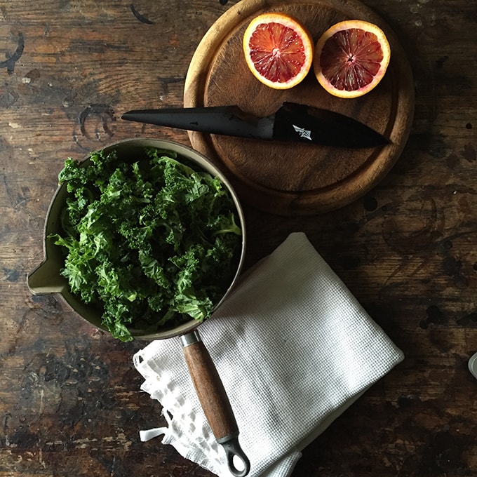 A table with oranges and a bowl of kale.