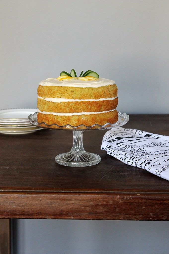 A cake on a stand sitting on top of a wooden table.