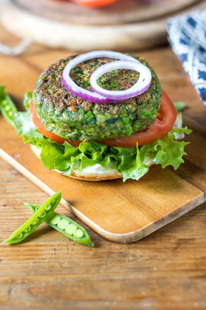 Burger with lettuce, tomato and onion, with the top bun off.