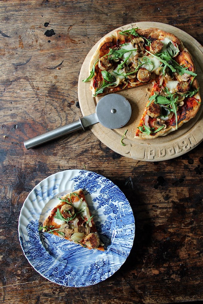 Vegetarian Sausage Skillet Pizza on a wooden board with pizza cutter. A slice on a vintage plate.