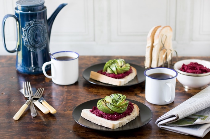 A breakfast table set up with coffee and toast topped with hummus and avocado.
