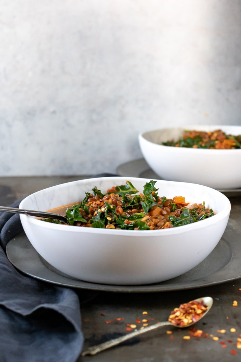side view of a bowl filled with hearty Lentil Stew, with kale.