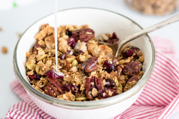 A bowl of granola with milk being poured in.