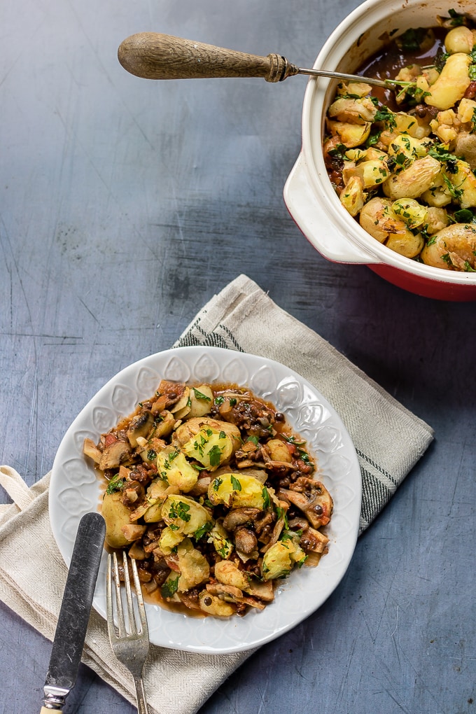 A plate of shepherd\'s pie next to a baking dish of it.