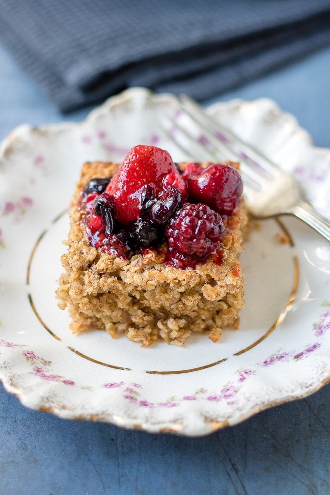 A slice of baked oatmeal topped with mixed berries on a vintage plate.