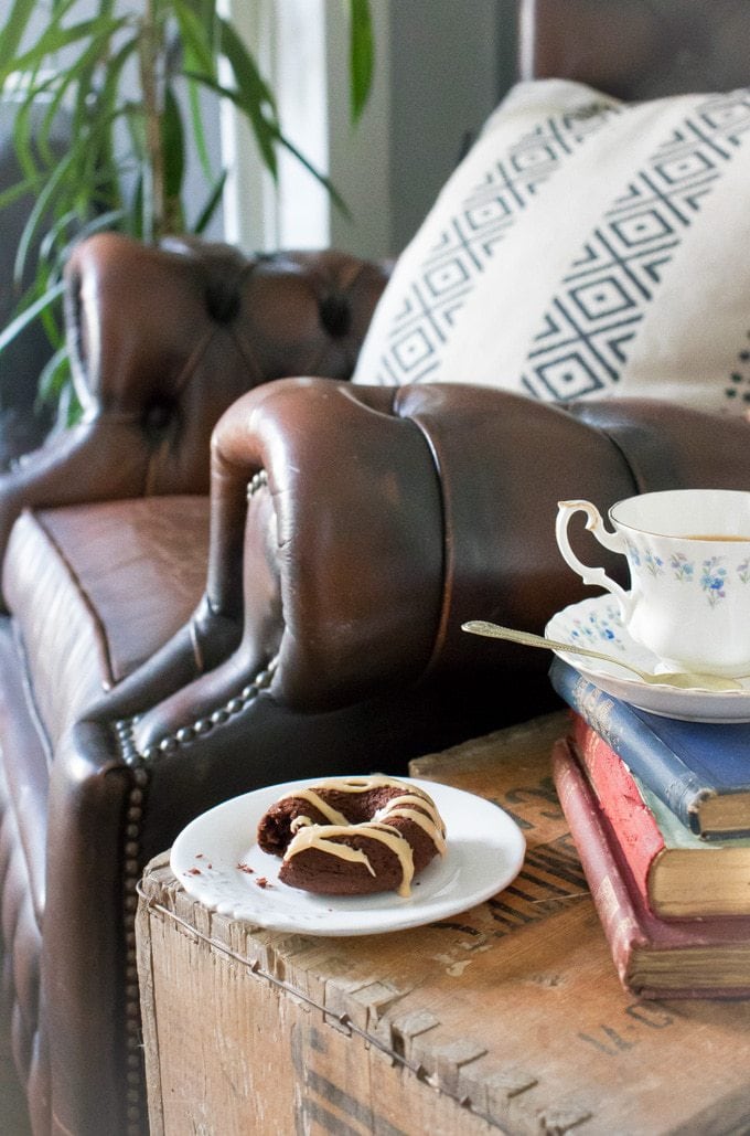 Vegan chocolate donut on a side table next to vintage books and teacup
