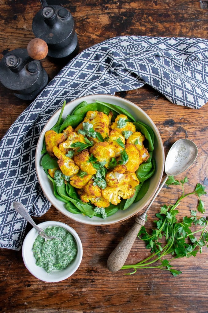 Bowl of spinach topped with roasted cauliflower.