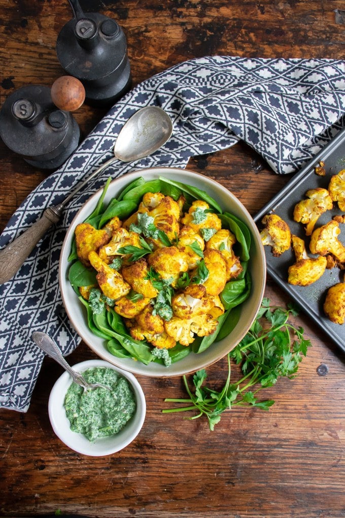 Table with bowl of spinach and roasted cauliflower.