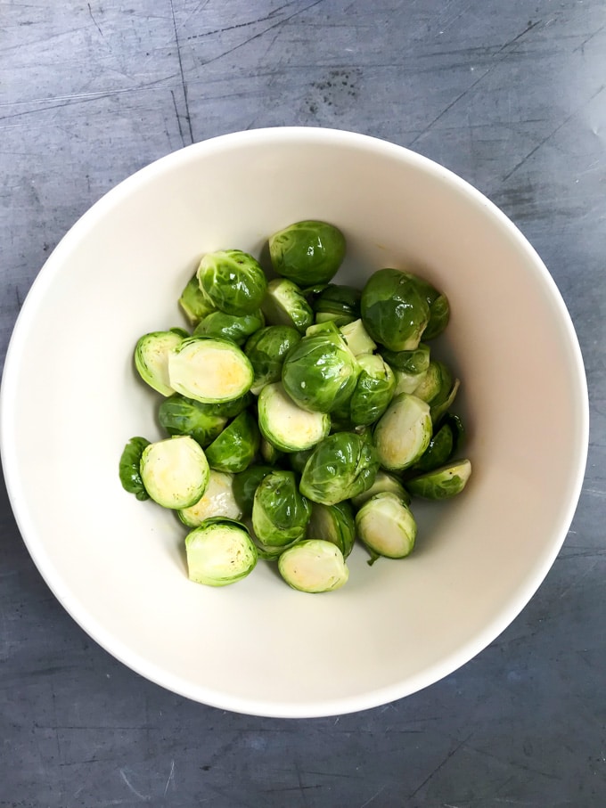 How to make a Roasted Brussel Sprout Christmas Tree (vegan gluten free side dish) - bowl of halved sprouts being tossed with oil
