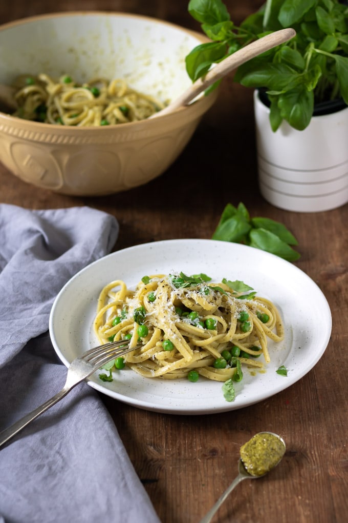 Plate of pasta, plus serving bowl full, on a table.