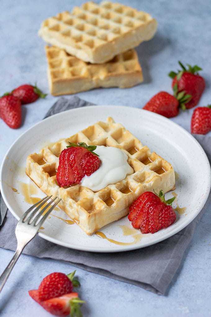 Table with a plate of waffles and strawberries.
