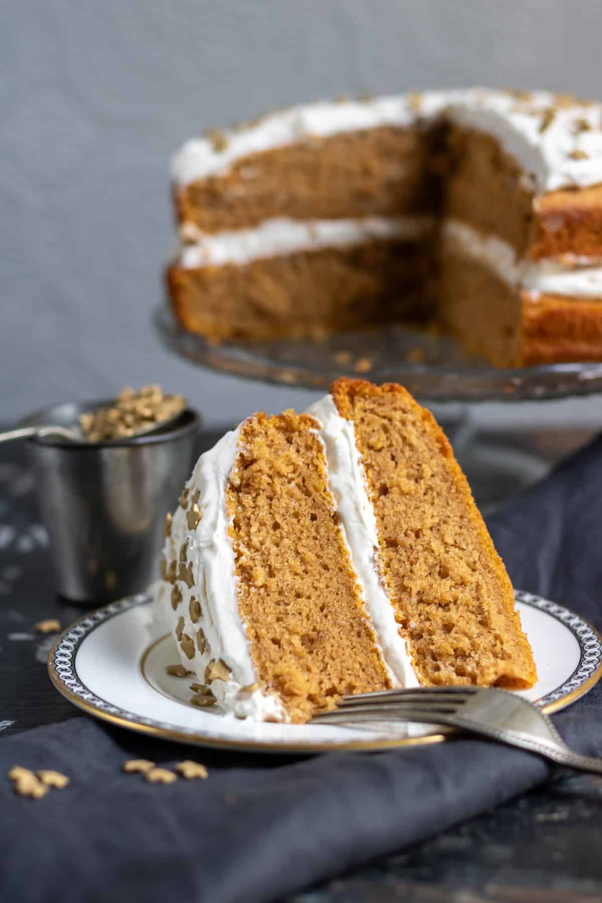 A slice of vegan pumpkin cake with ginger frosting on a plate.