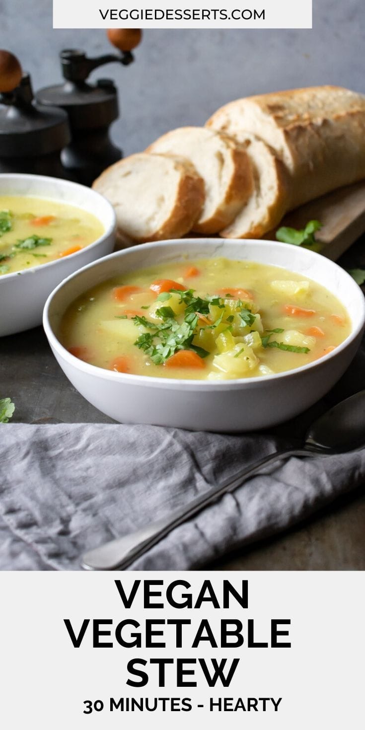 Close up of a bowl of vegetable stew topped with parsley. Bread in the background.