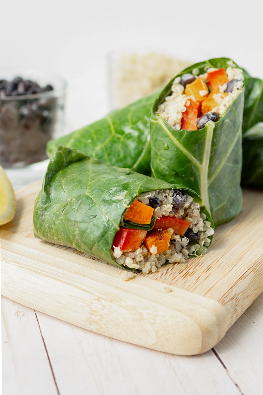 collard wraps with quinoa and sweet potato cut on a wooden board.