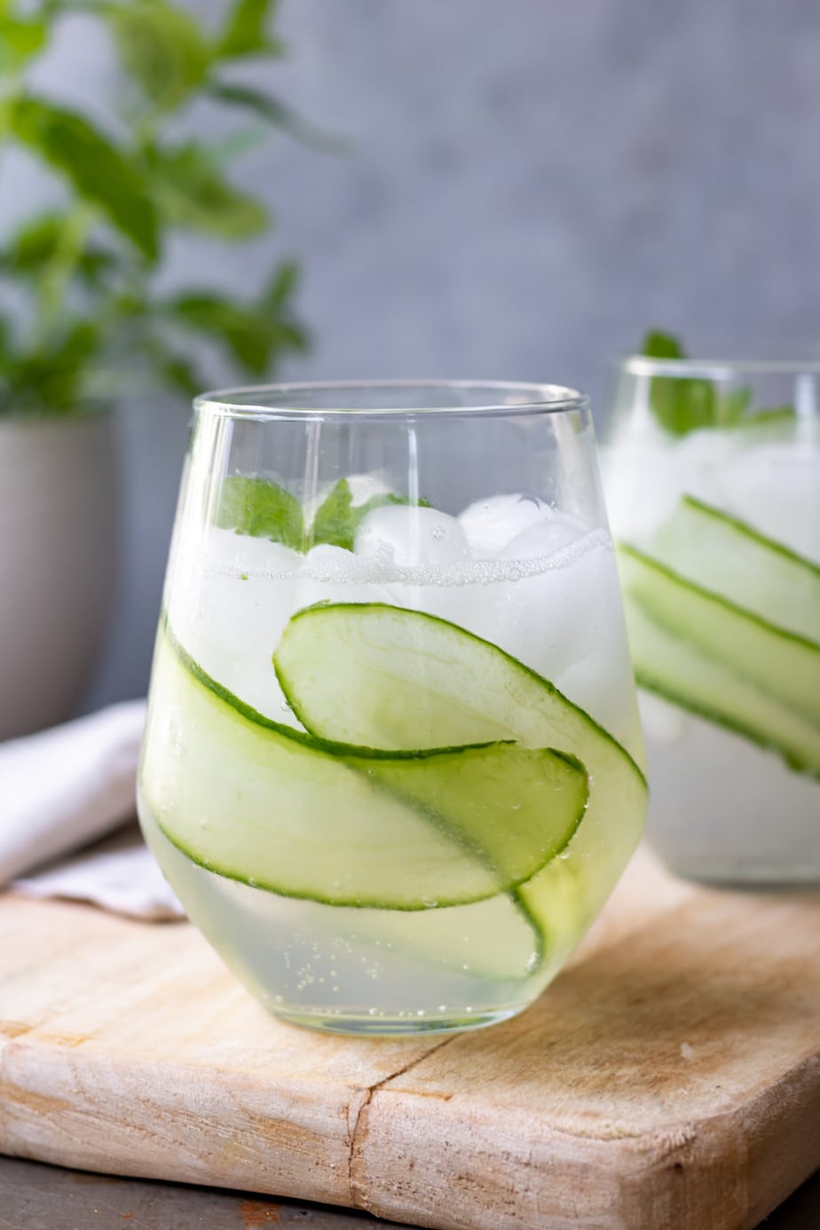 Glass of cocktail with ice and slices of cucumber.