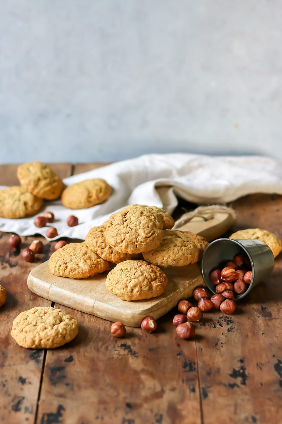 Pile of cookies on a board next to hazelnuts.