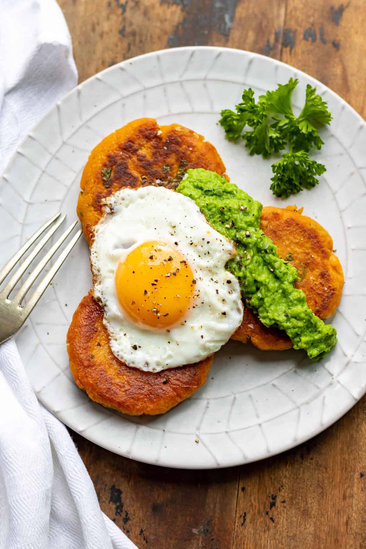 Plate of sweet potato patties topped with pea puree and a fried egg.