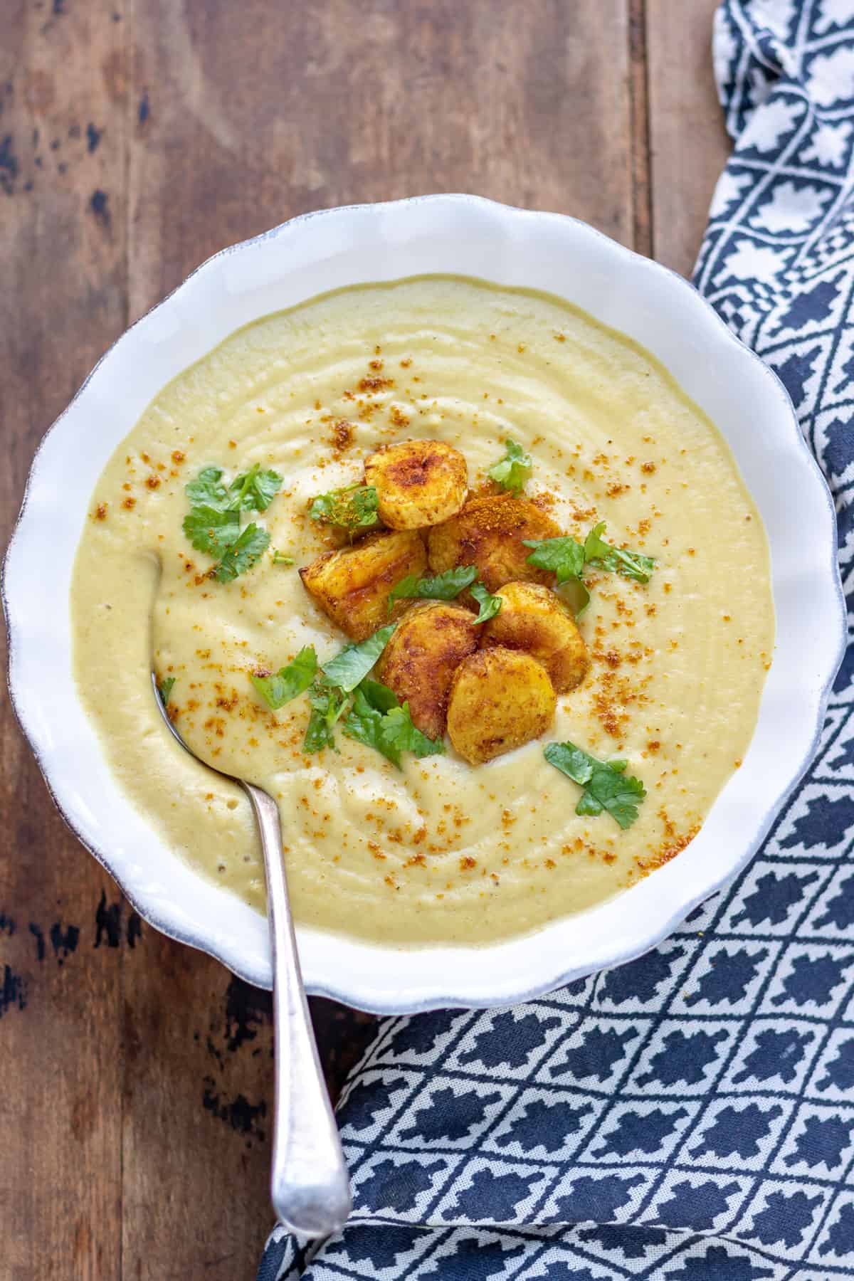 Bowl of soup with slices of roasted parsnip on top.