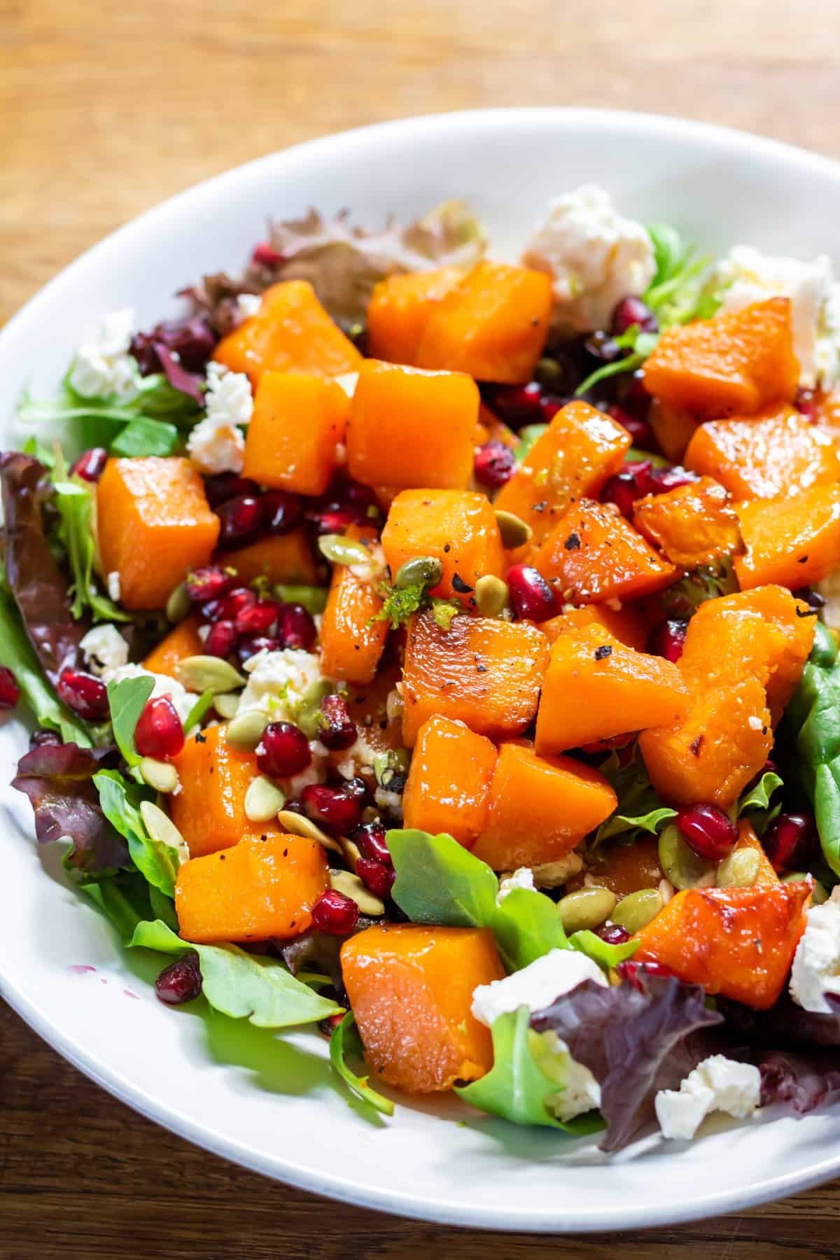 Close up of a serving dish of roasted butternut squash salad on a table.