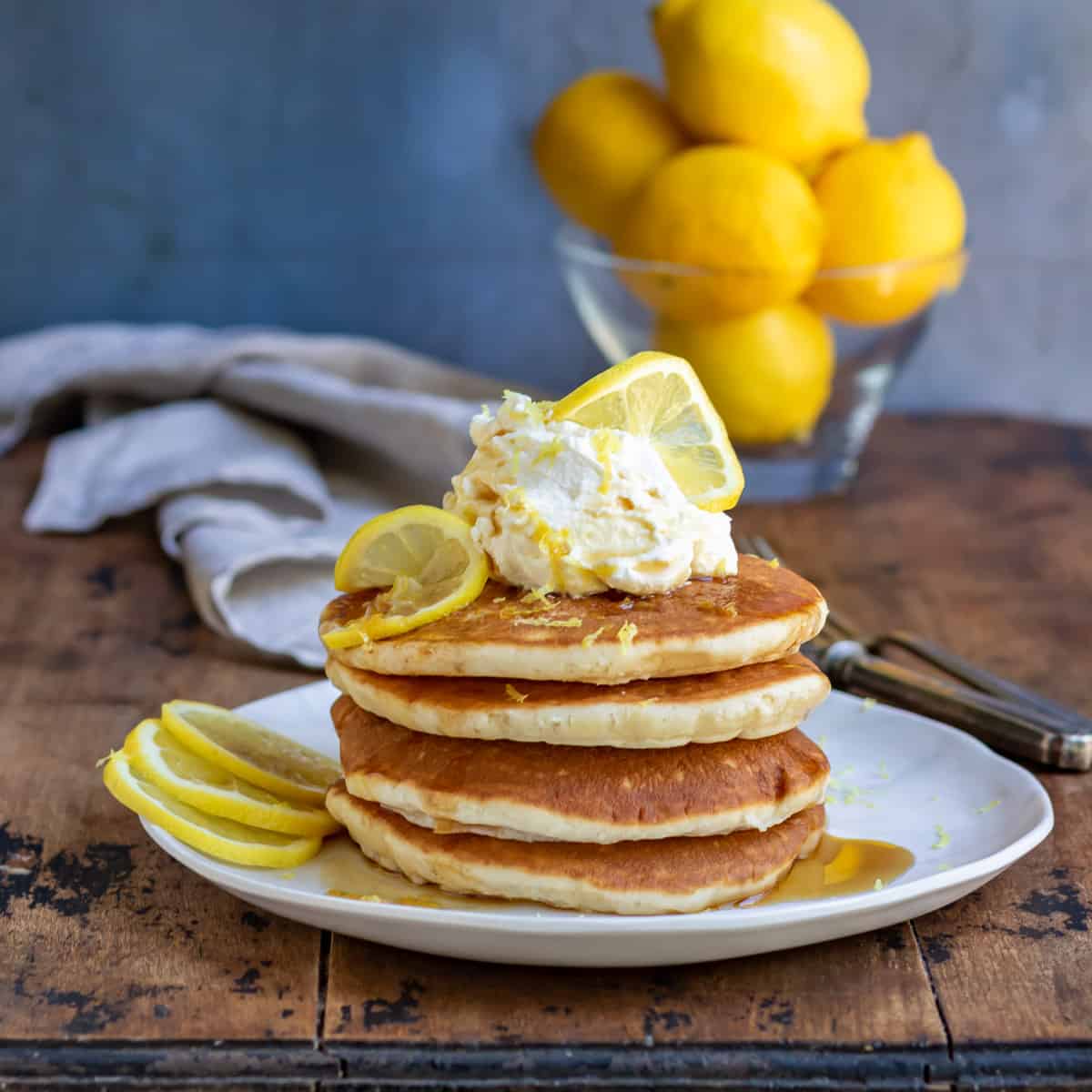 Wooden table with a plate of lemon pancakes.