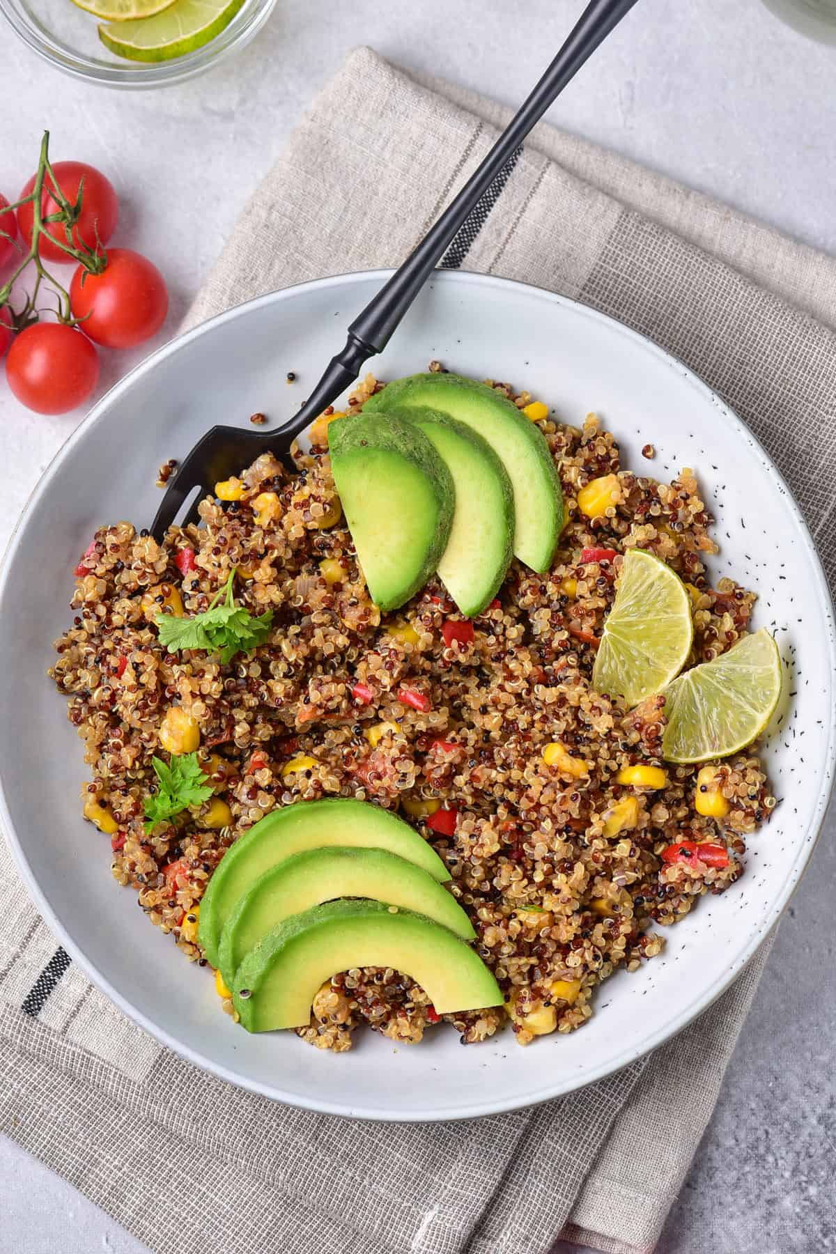 Table with a bowl of mexican quinoa salad topped with slices of avocado.