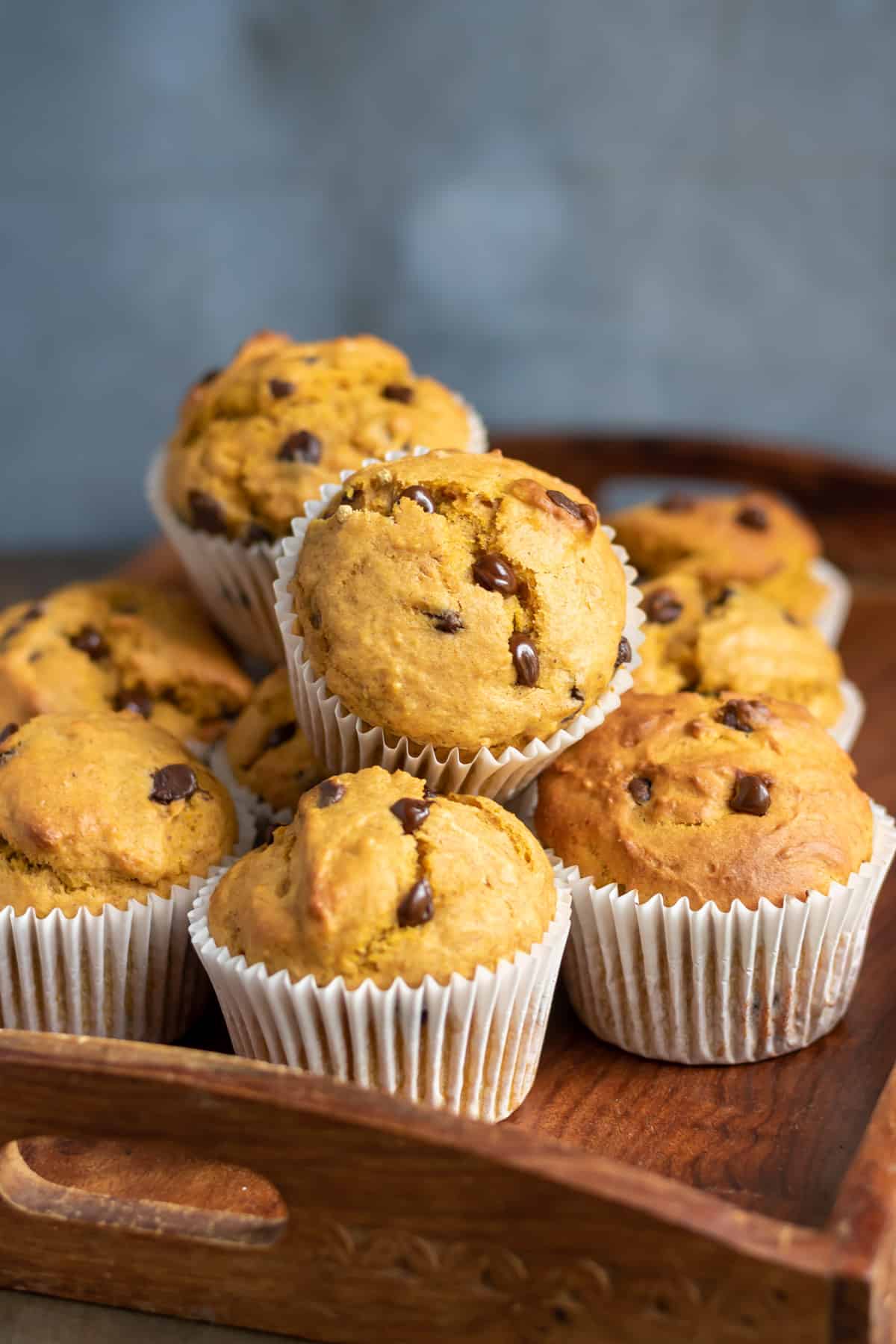 Pile of pumpkin banana muffins on a wooden tray.
