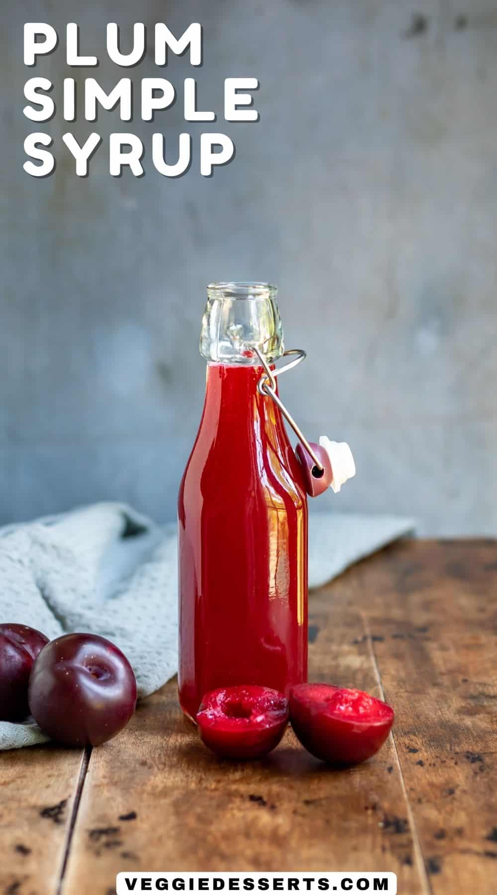 Botton on a wooden table, and text Plum Simple Syrup.