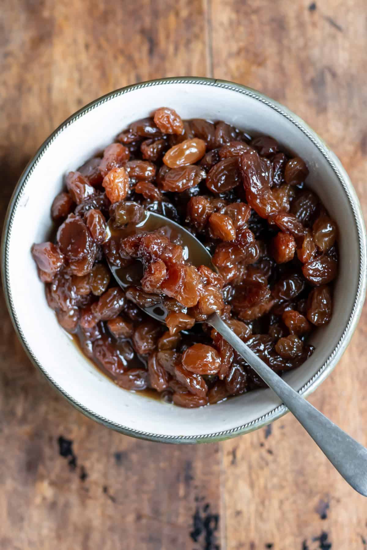 A spoon in a dish of raisin compote.