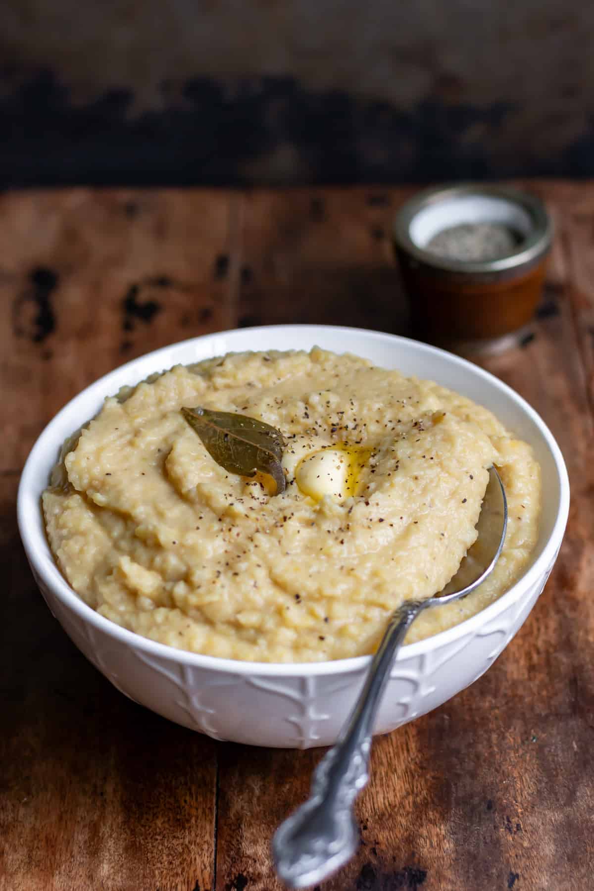 Side view of a bowl of pease pudding with a spoon in it.