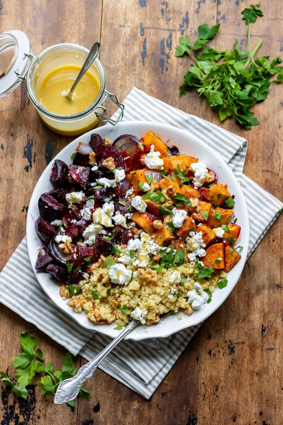 Looking down at a table with a serving dish of roasted beetroot and sweet potato salad with couscous.