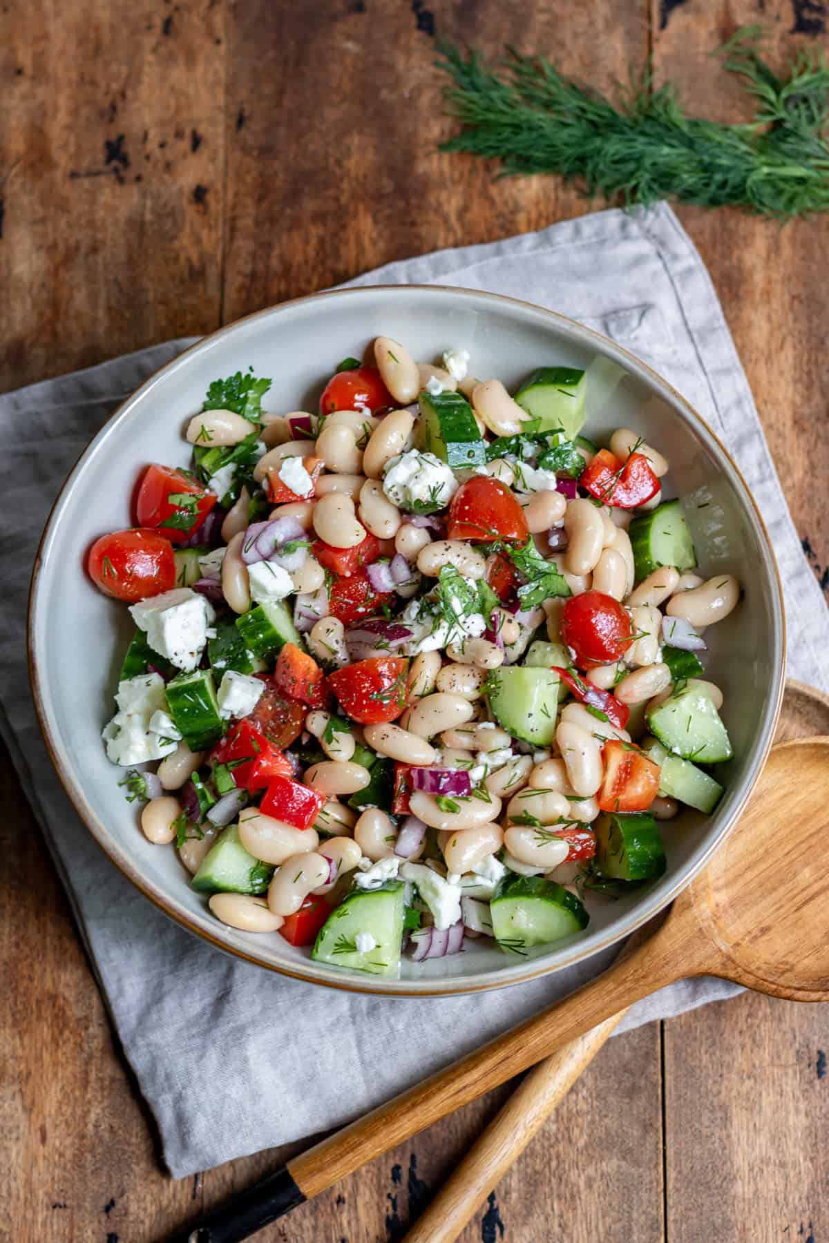 A table with a serving dish of greek bean salad.