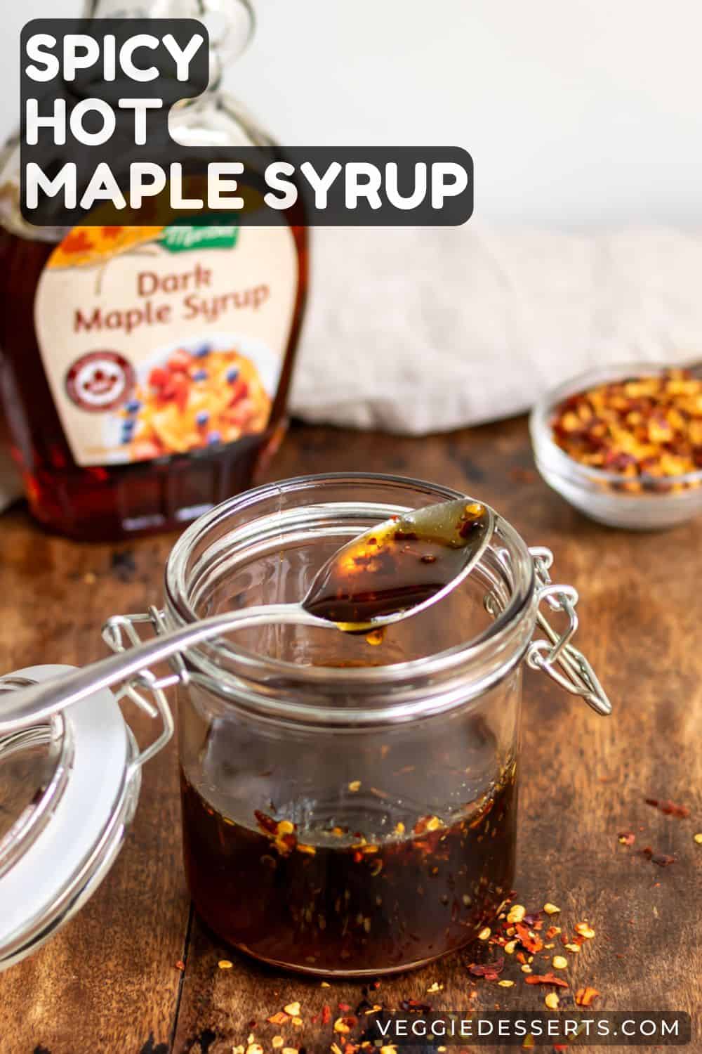 Jar of syrup on a table, next to chili flakes, with text: Spicy Hot Maple Syrup.