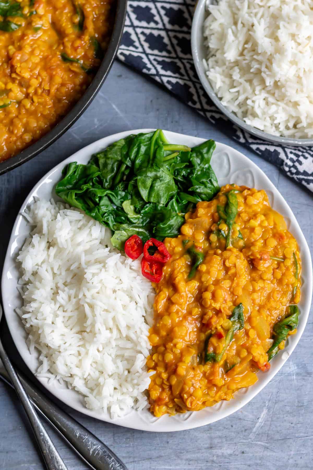 Close up of a plate of red lentil dal with rice and spinach.