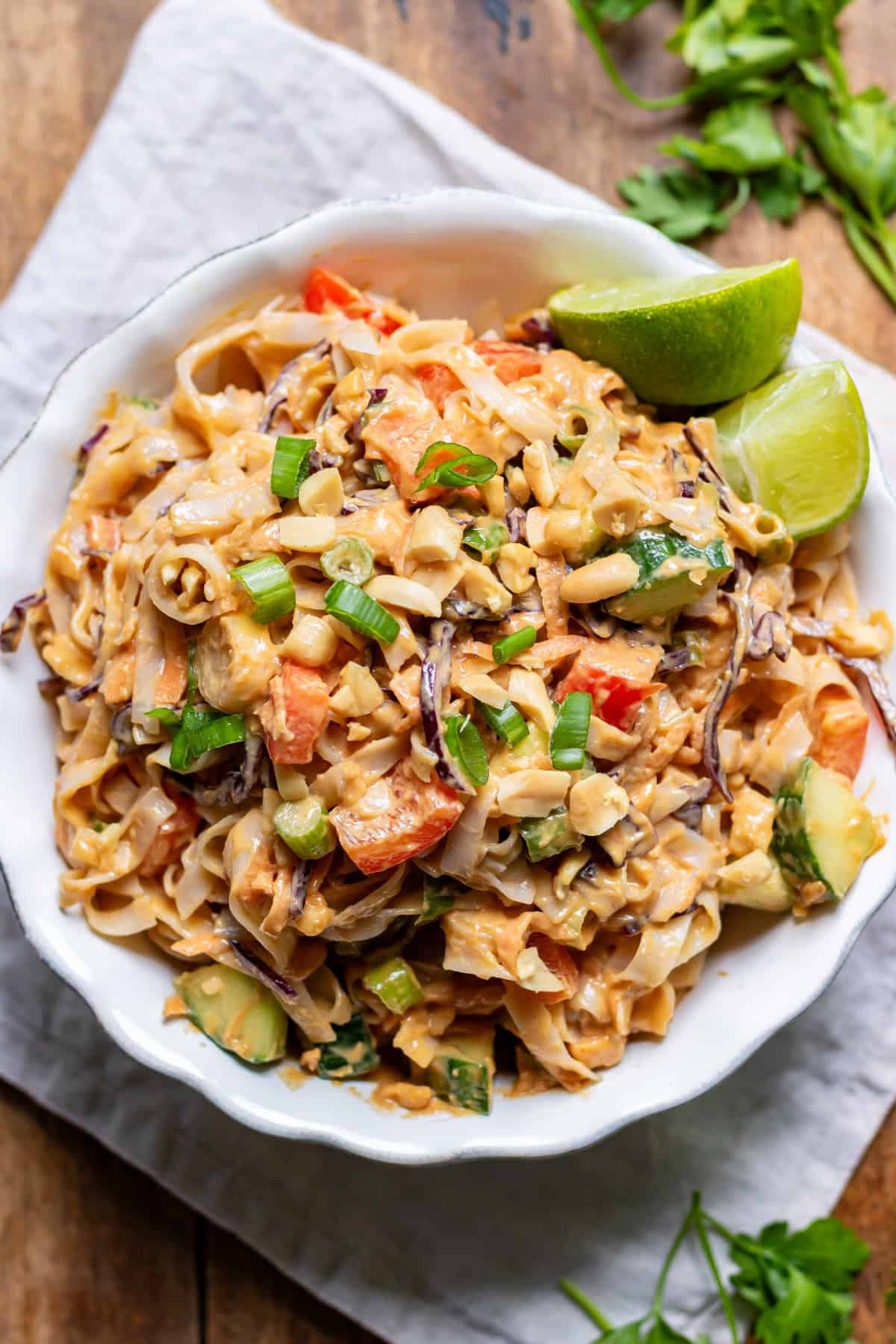 Looking down at a serving dish of peanut rice noodle salad on a wooden table.