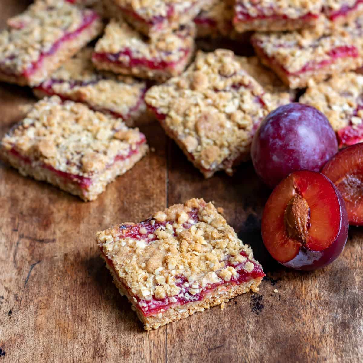 A wooden table with a plum bar in front of more plum bars.